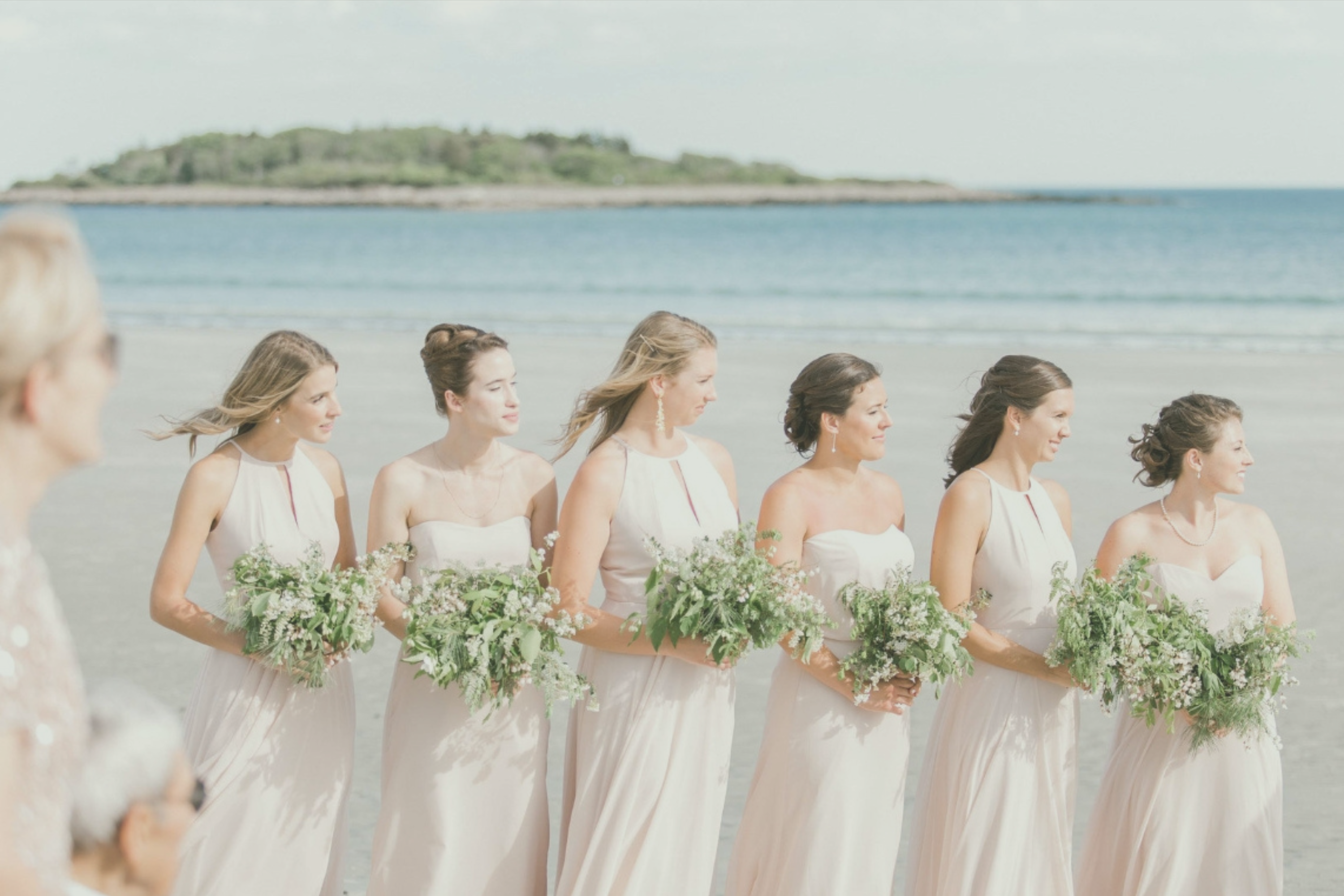 Bridesmaids on a beach holding bouquets made by stem & vine wedding flower services in Southern Maine
